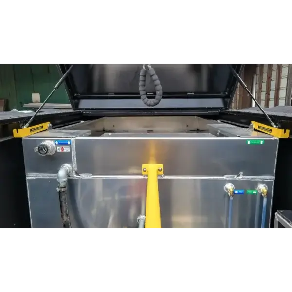 A close-up of the Wildcat 1150, showing its open metal container with a hinged black lid, yellow handles, control labels, and attached pipes—equipment used by Canada firefighters for wildfire response.