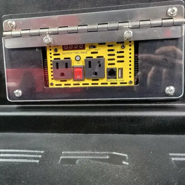 The Wildcat 950 power inverter panel—perfect for wildfire equipment in Canada—features two AC outlets, a red power switch, USB and remote ports, wattage indicator lights, all secured behind a clear hinged protective cover.